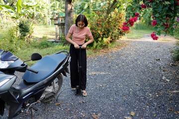Woman pumping air into a motorcycle tire.