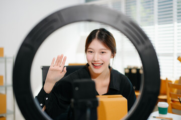 Beautiful Asian lady blogger showing clothes in front of the camera to recording vlog video live...