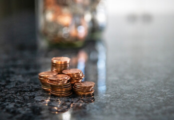 Close up macro image of coin stacks with jars of coins in the background -- with shallow depth of field. Pennies are no longe being made by the U.S. Mint.