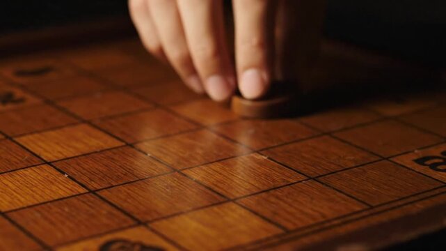 A focused player's hand carefully moving a wooden checker piece across a vintage board, symbolizing strategy, competition, and intellectual challenge