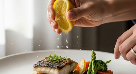Lemon juice being squeezed onto a plate of fish and vegetables.