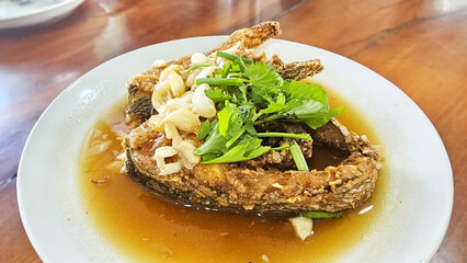 Golden Fried Fish Delight: Savor the delicious sight of crispy fried fish, glistening in a savory sauce. Adorned with fresh herbs, garlic, a culinary experience in itself.