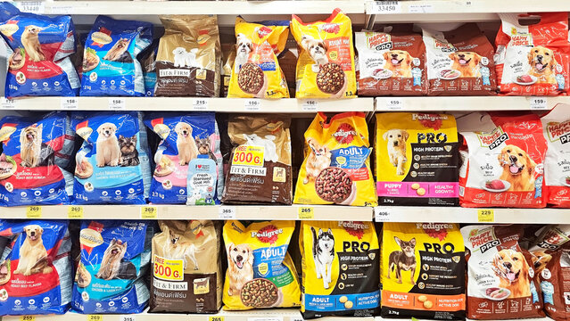 A colorful display of various dog food brands arranged neatly on a supermarket shelf, showcasing different package sizes and types. Thailand, November 28, 2025