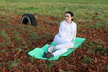 Woman doing morning exercises on a mat outside