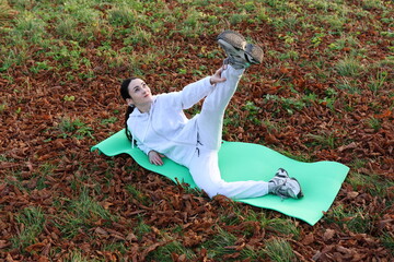 Woman doing morning exercises on a mat outside