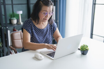 Fototapeta premium Mature Asian woman Work from home. senior&nbsp;asian woman on laptop with technology concept.