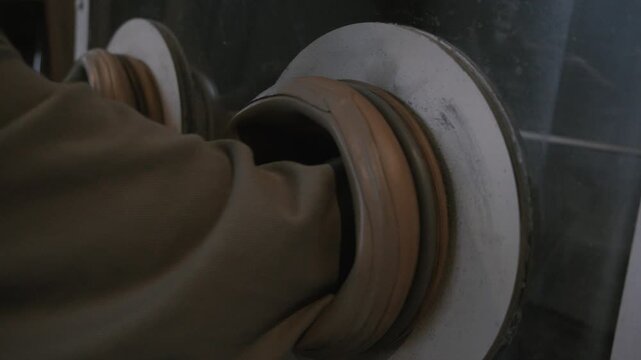 Laboratory scientist putting hands into glovebox