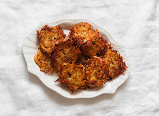 Crispy latkes potatoes on a white plate on a light background, top view