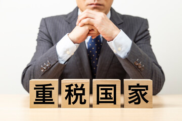 「重税国家」と書かれたブロックとビジネスマン