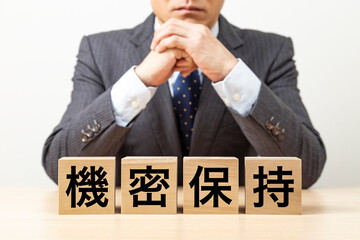 「機密保持」と書かれたブロックとビジネスマン