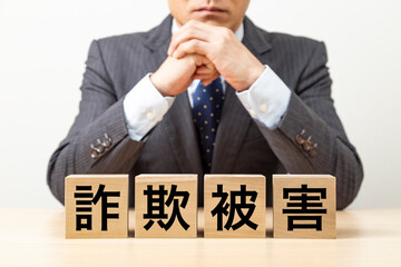 「詐欺被害」と書かれたブロックとビジネスマン