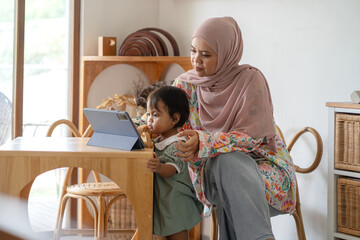 Indonesian Muslim Woman Remote Working with Child at Home