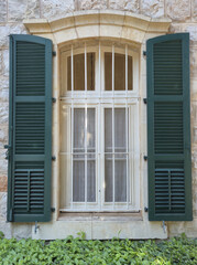 Classic window with white frame and green wooden shutters