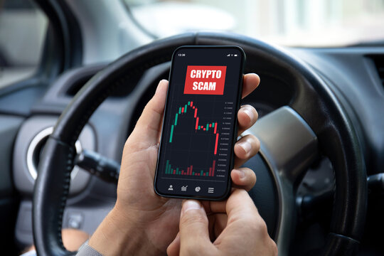 male hand hold phone with chart scam crypto coins car