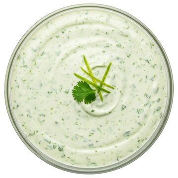Overhead view of creamy cilantro lime dressing garnished with zest in a glass bowl on transparent background