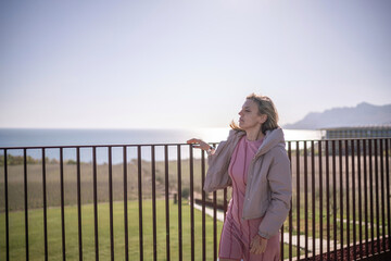 Obraz premium Woman vacation balcony railing watching sunrise over sea mountain landscape