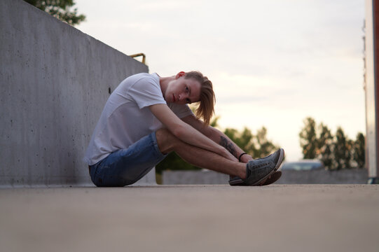 a guy with long hair bowed his head to his feet while sitting on the ground