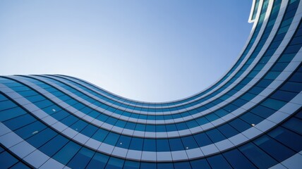 Low angle view of a modern building with blue glass facade against a clear blue sky on a sunny day