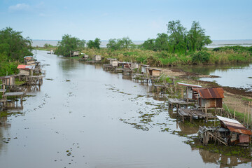Traditional fisherman  wooden huts  of indigenous people on riverside or canal with boat at Phatthalung province ,Thailand.