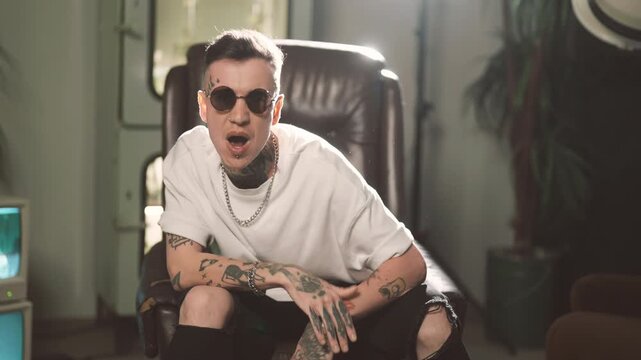 Recitative and singing, cool rap artist performing hip-hop song, portrait. Filming music video in studio, self-expression and talent, hobby of young man with tattoos, freedom of contemporary art