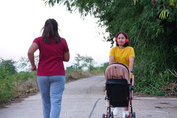 The woman in the yellow shirt is pushing a stroller, while her friend in the red shirt is running ahead.
