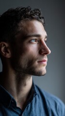 Obraz premium Profile of a young man in deep thought, gazing sideways, lit by soft natural light against a subdued background.