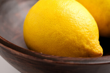 Ripe yellow whole lemons in a wooden bowl. Minimalist view