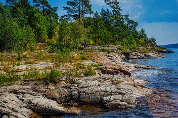 Rocky Forested Shoreline by Calm Blue Water