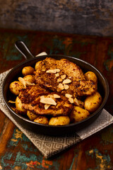Fried pork steaks in a frying pan with potatoes. Rustic wooden background. Soft focus.	