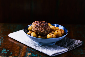 Fried meatballs with potatoes on a rustic background. Selective and soft focus.	