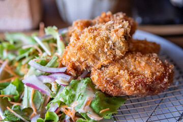 Crispy fried chicken served with fresh salad on a plate in restaurant
