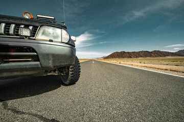 Extreme low-angle close-up of an off-road vehicle's front tire on asphalt in Mongolia. Tread...