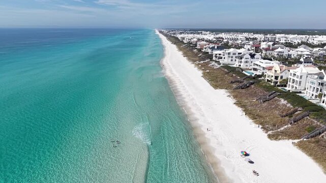 Drone fly over long stretch of turquoise Gulf of Mexico coastline with white luxury real estates, 30A, Florida, USA
