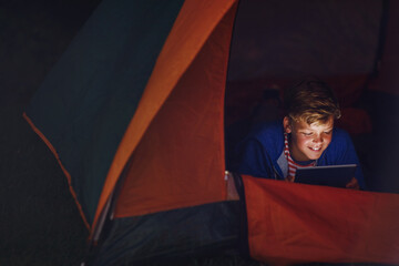 Night, kid outdoor and tablet in tent with smile for reading ebook, playing game or adventure...