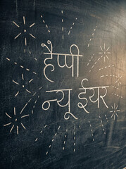 Fototapeta premium Happy new year message in hindi, chalk art on a dark blackboard with festive sparkler drawings