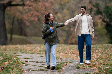 Fototapeta premium Happy multiethnic couple holding hands walking in autumn park