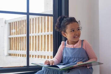 Adorable little girl engrossed in her storybook adventure indoors