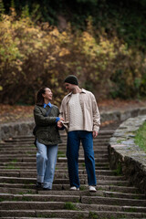 Fototapeta premium Couple holding hands walking down park stairs