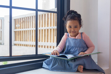 Adorable little girl engrossed in her storybook adventure indoors