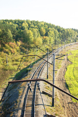 Siberian forest and empty railroad tracks with overhead catenary system stretching into distance. Symbolizes remote transportation routes, regional connectivity and sustainable mobility infrastructure