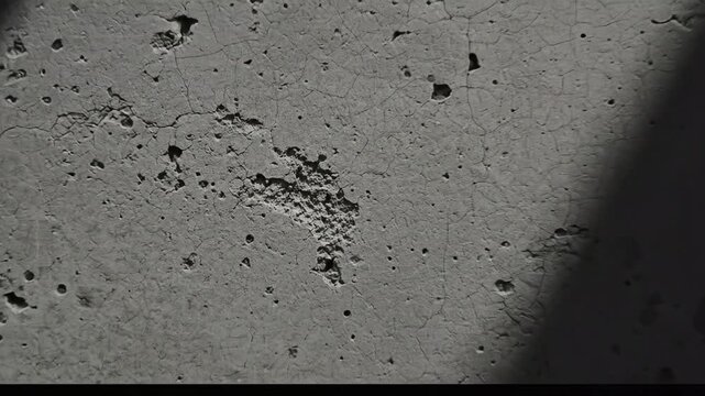 Gritty Concrete Surface with Imperfections and Cracks, Textured Gray Wall Background with Dramatic Diagonal Shadow