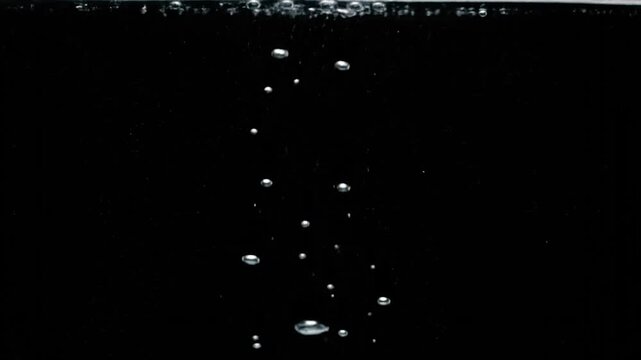 Bright, shimmering air bubbles of various sizes ascend in dark water, forming a dynamic pattern