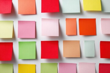Abstract vibrant background of multi-colored adhesive sticky notes arranged in a grid pattern on a white surface, ideal for brainstorming, planning, and reminders