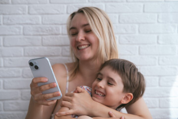 Happy blonde mother and little son laughing together, have good time. Enjoying life concept.