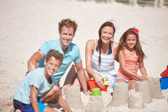 Sandcastle, portrait and travel with family at beach for summer vacation, bonding and game. Support, holiday getaway and toys with parents and children playing with sand outdoor for adventure