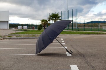 Black umbrella on empty parking lot