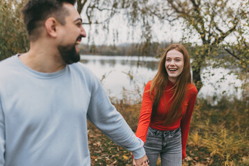 Obraz premium couple peacefully enjoying fall by water, traveling couple relaxing along lakeside in autumn sunshine