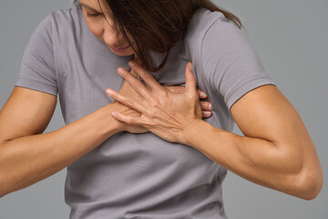 Close-up of woman clutching chest in pain, eyes closed, expressing discomfort 