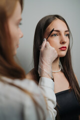 studio environment with technician accurately marking eyebrows during beauty assessment session