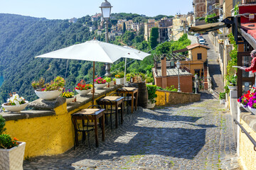Fototapeta premium Scenic view of Castel Gandolfo in Lazio, Italy, showcasing quaint restaurant tables nestled against the town's tranquil backdrop. 